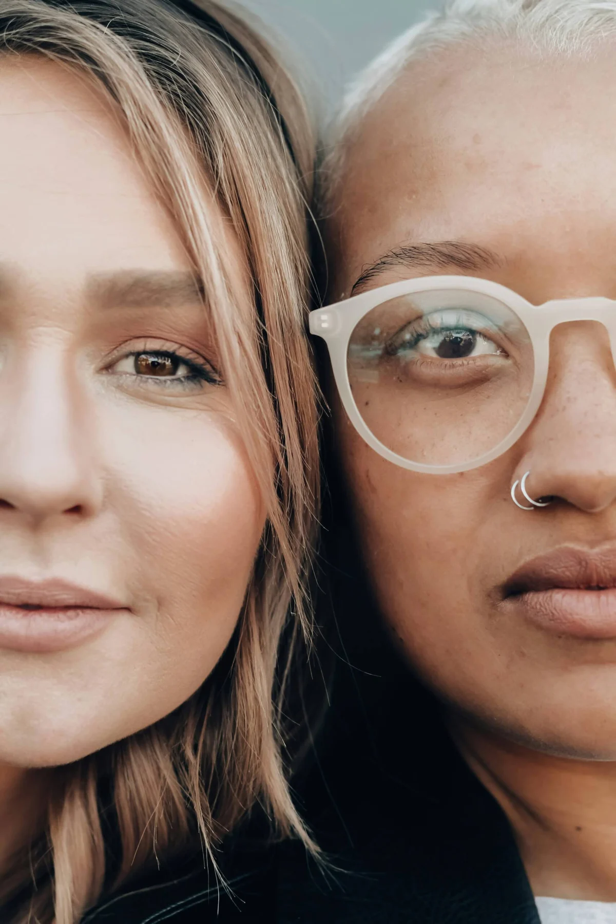 Close-up portrait of two diverse women, one with blonde hair and one wearing glasses.