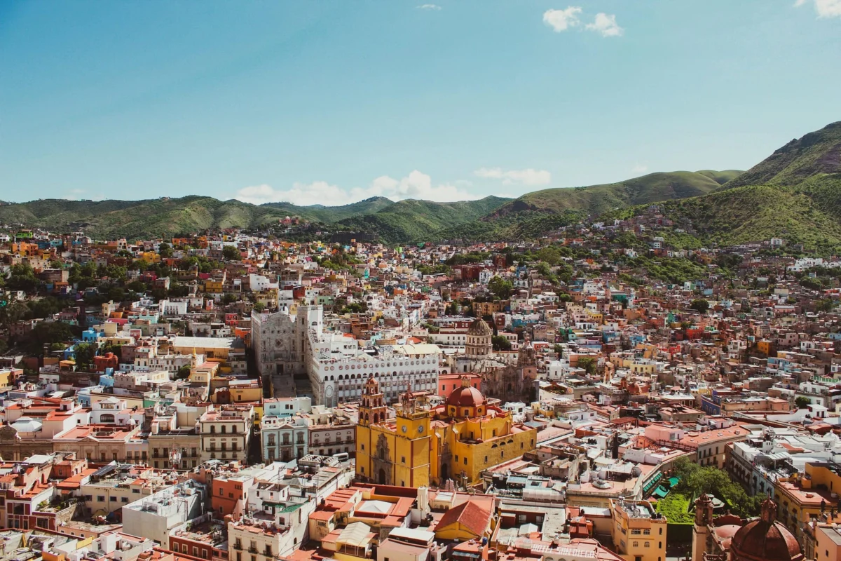 Aerial view of colorful buildings and historic architecture in Guanajuato, Mexico, surrounded by hills.