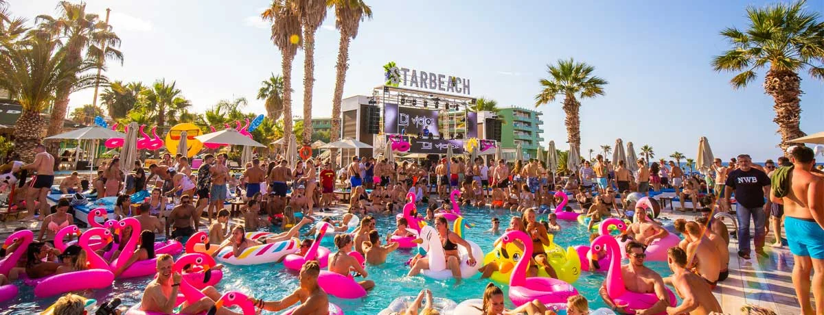 A crowded outdoor pool party at Starbeach with people on colorful inflatable floats.