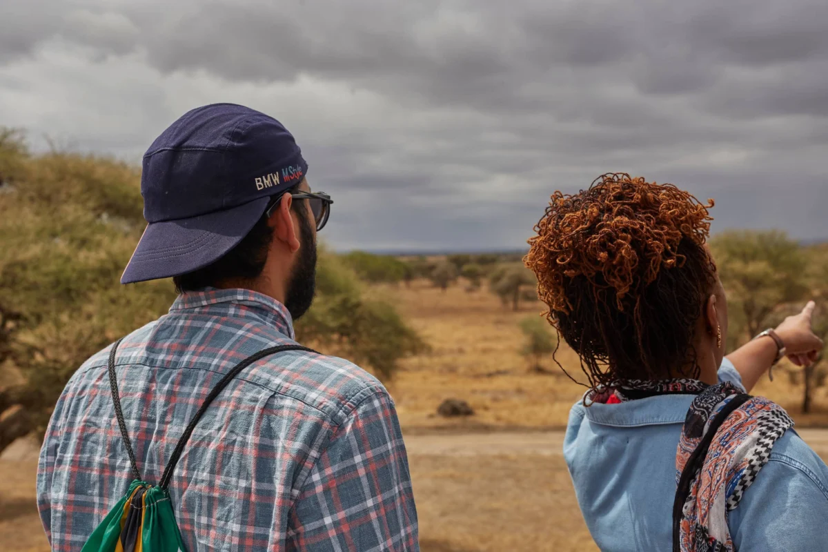 Two people looking out over a dry landscape, with a woman pointing into the distance.