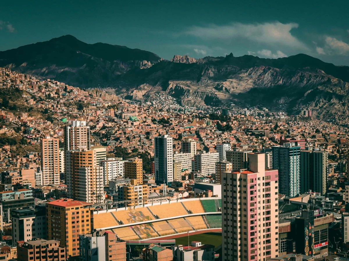 Panoramic view of La Paz showing a stadium, tall buildings, and a mountain backdrop.