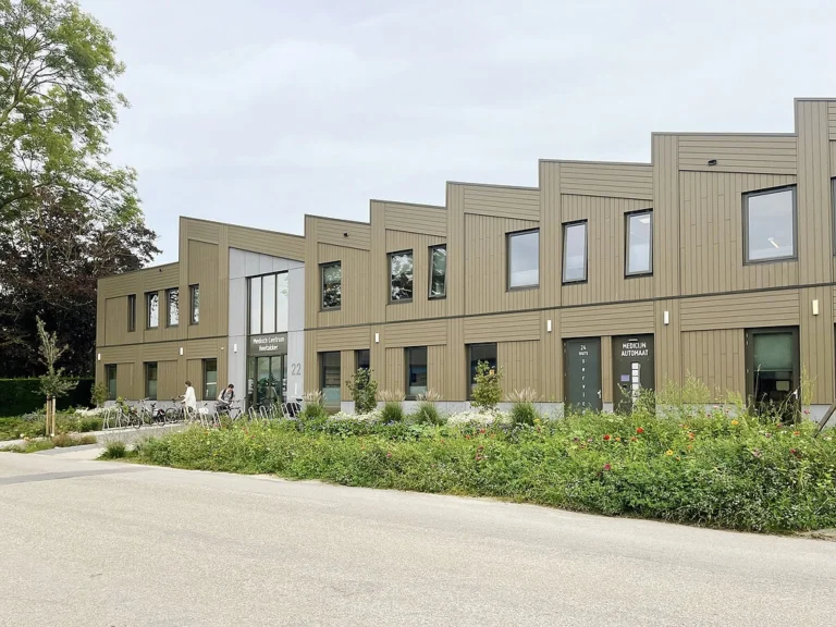 Exterior of Medisch Centrum Houtakker in Bemmel with modern wooden cladding and flower beds.