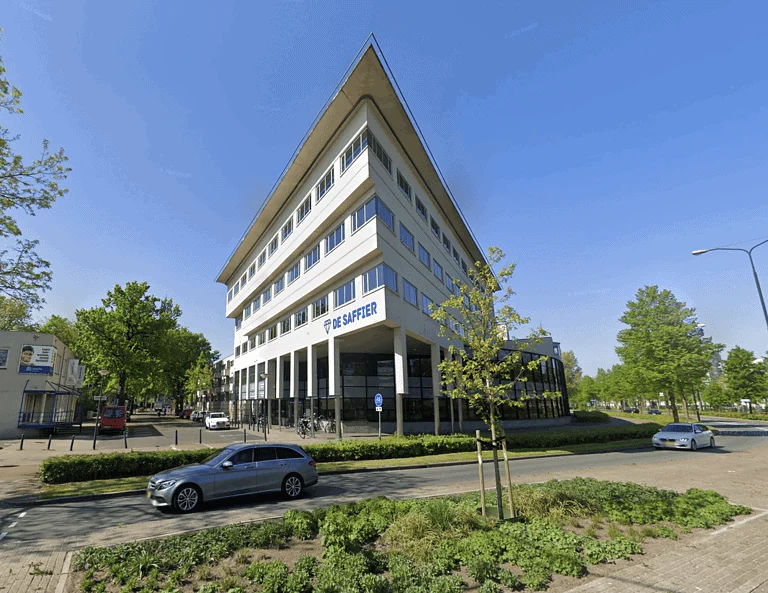 Triangular modern office building De Saffier along a tree-lined street in Apeldoorn.