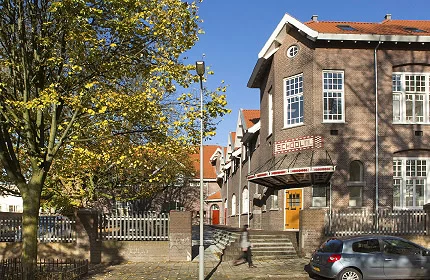 Historic brick building with entrance steps beside golden autumn trees in Arnhem