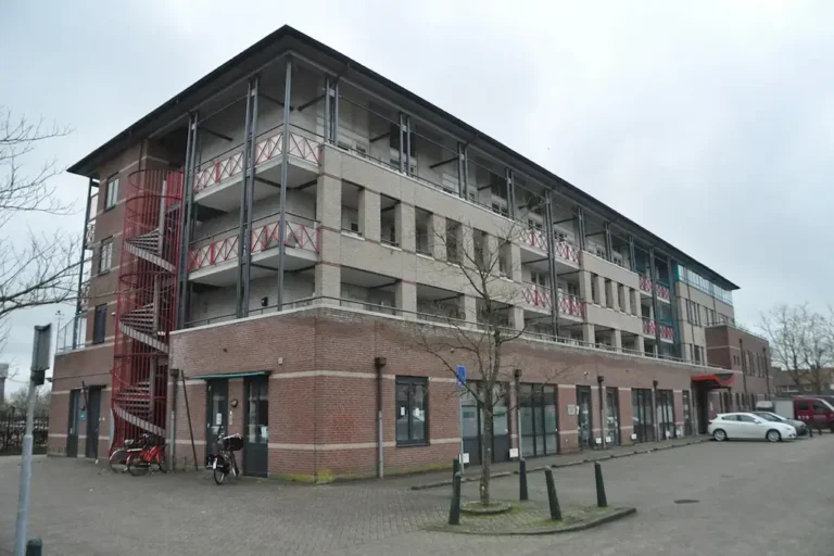 Multi-story brick building in Culemborg featuring balconies and an exterior red spiral staircase.