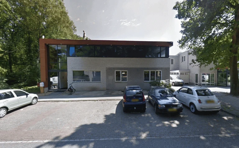 Modern two-story office building in Doorwerth with cars parked in the front lot