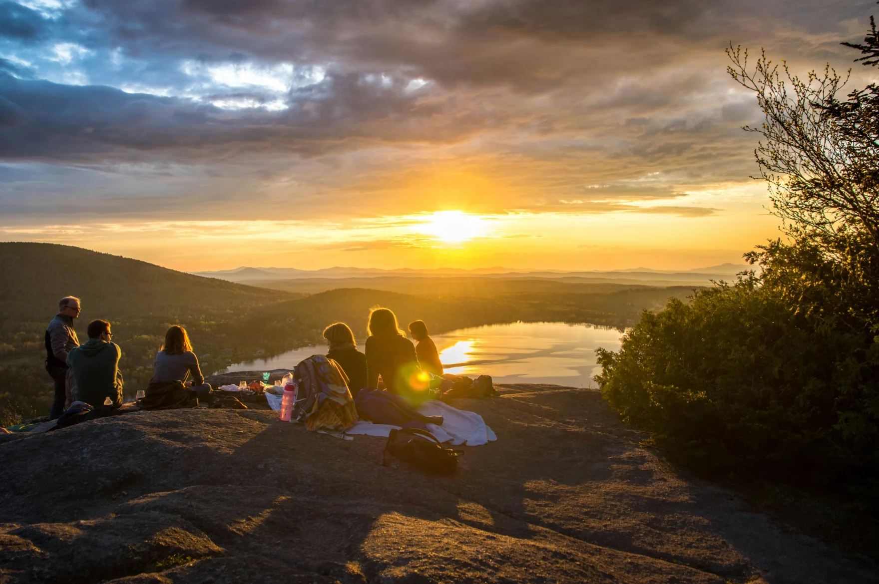 Groep vrienden kijkt naar de zonsondergang boven een meer