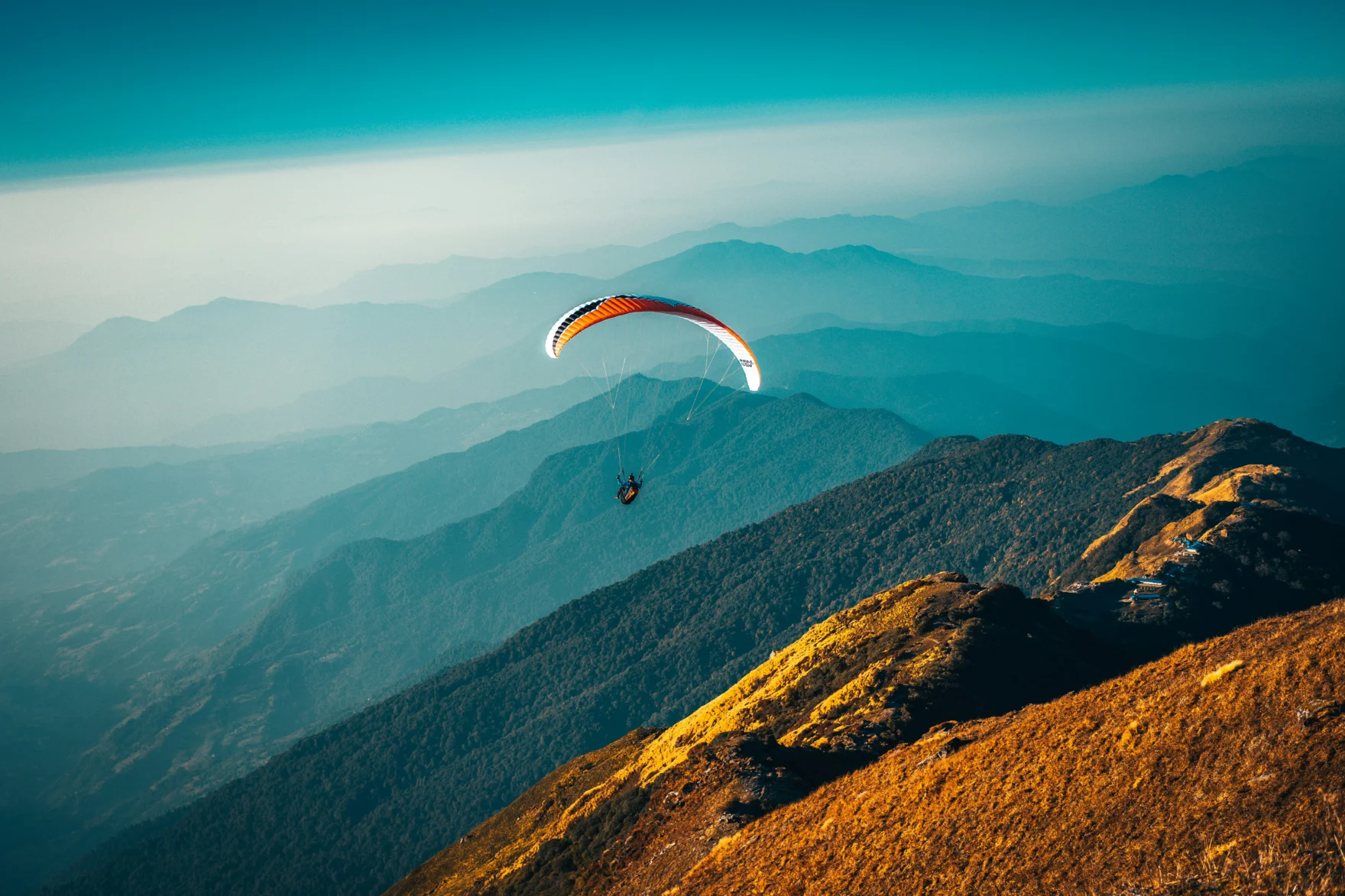 Paraglider boven groene berghellingen