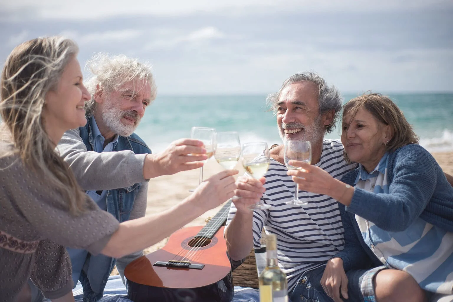 Groep senioren proost met elkaar aan het strand