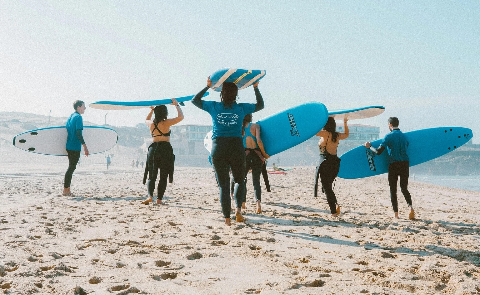Surfers lopen met hun boards over het strand