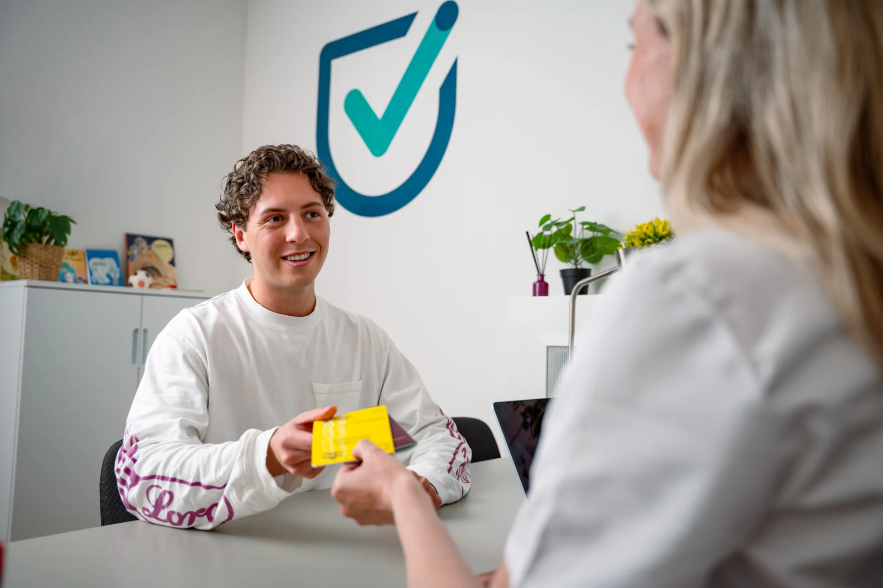 Reiziger krijgt het gele vaccinatieboekje van een medewerker