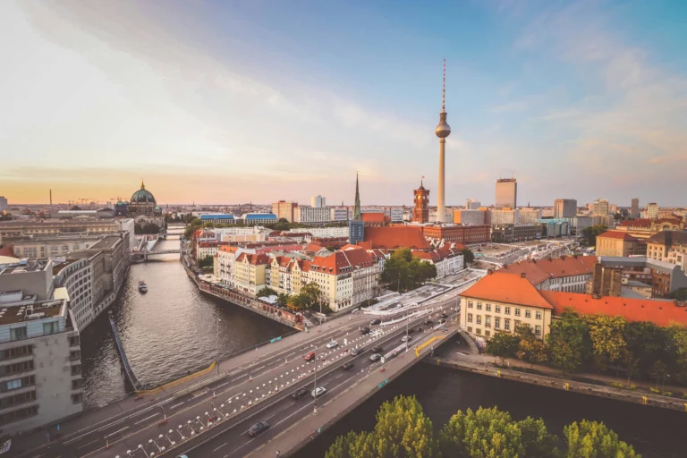 Berlin cityscape along the Spree River featuring the Fernsehturm TV tower at sunset
