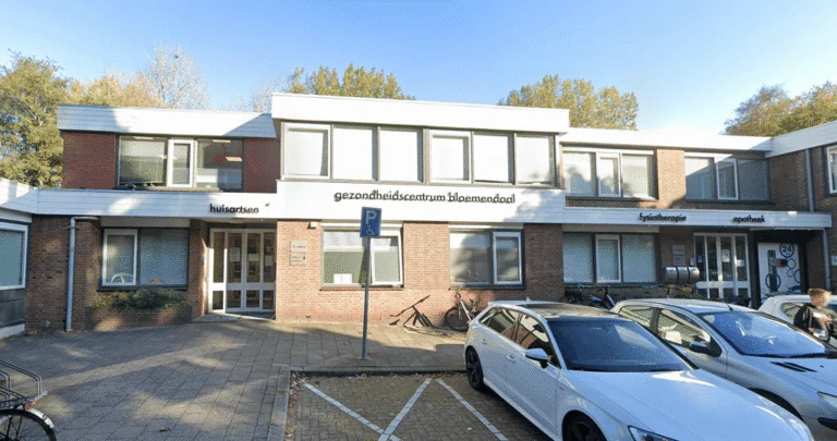 Exterior of the Bloemendaal health center building in Gouda with parked cars.
