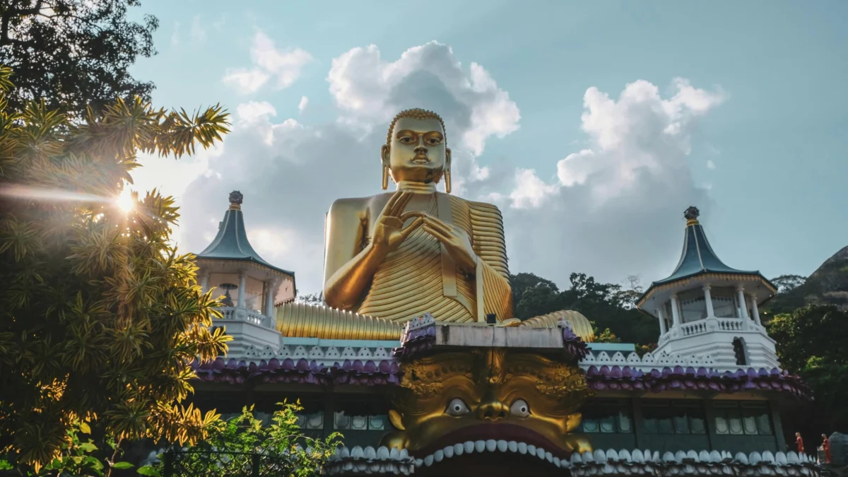 Giant golden Buddha statue atop the Golden Temple of Dambulla under bright sunlight