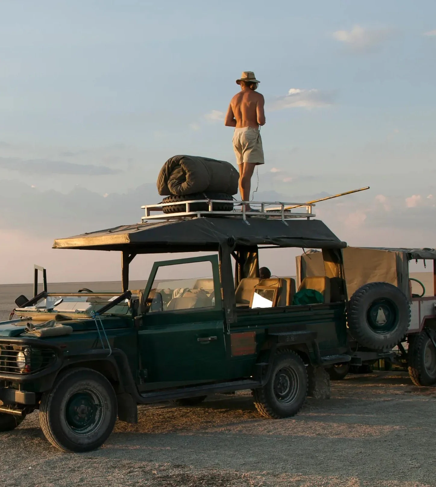 Reiziger op het dak van een safarivoertuig bij zonsondergang