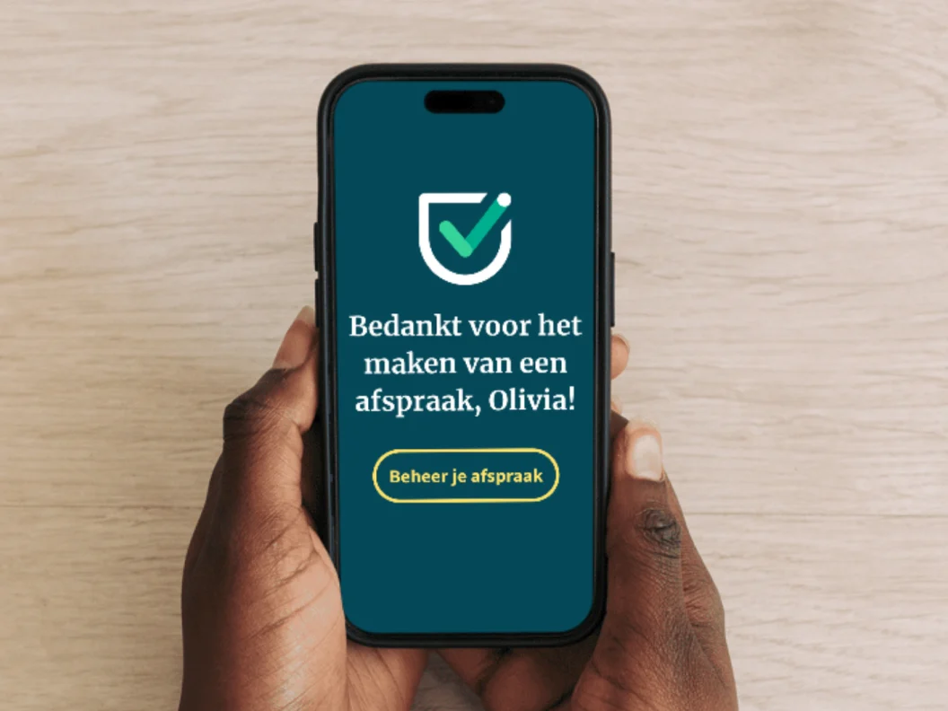 Handen met een telefoon waarop de Vaccinatiepunt-app staat