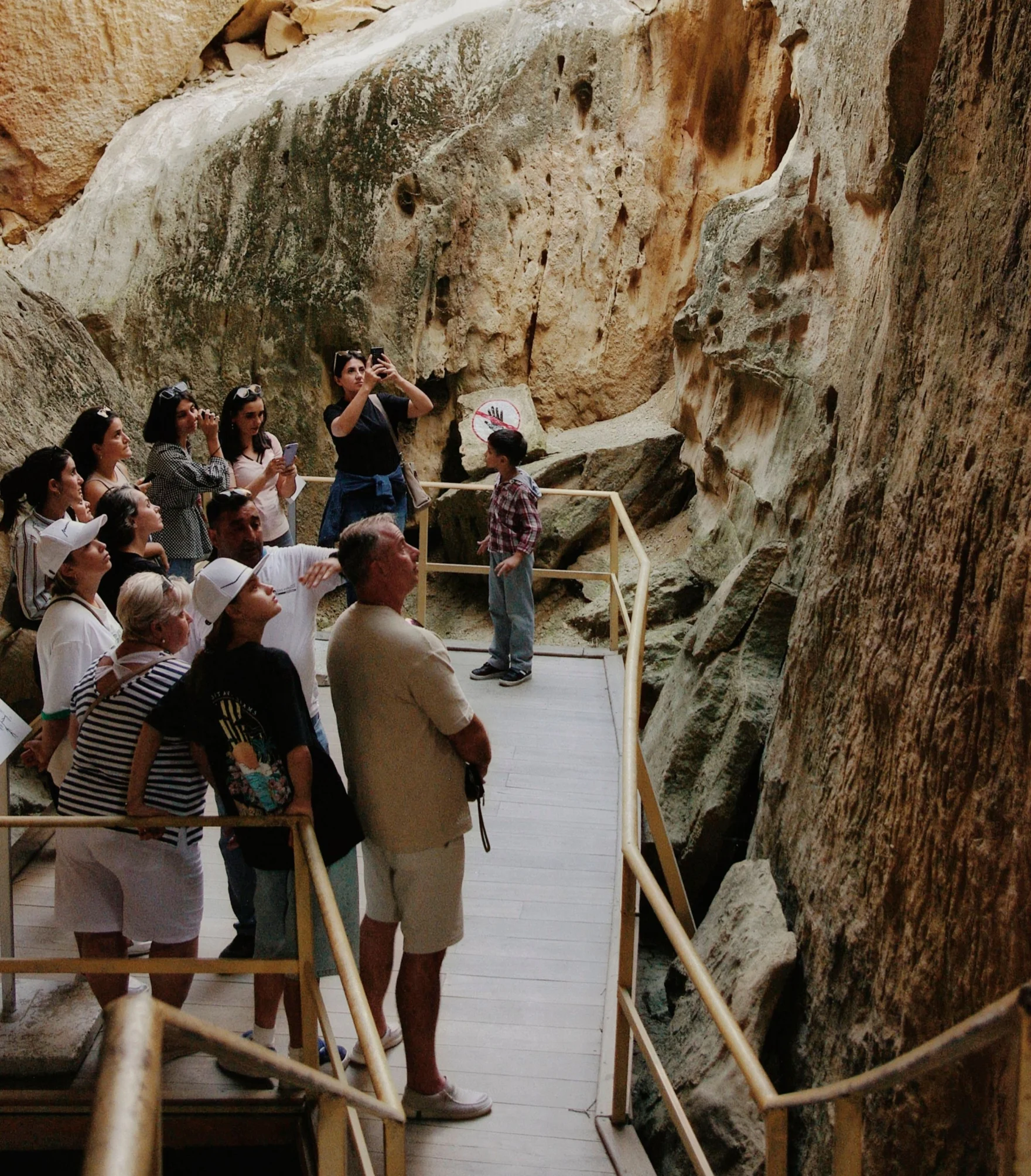 Tourists on a wooden walkway looking up at towering rock formations in a cave